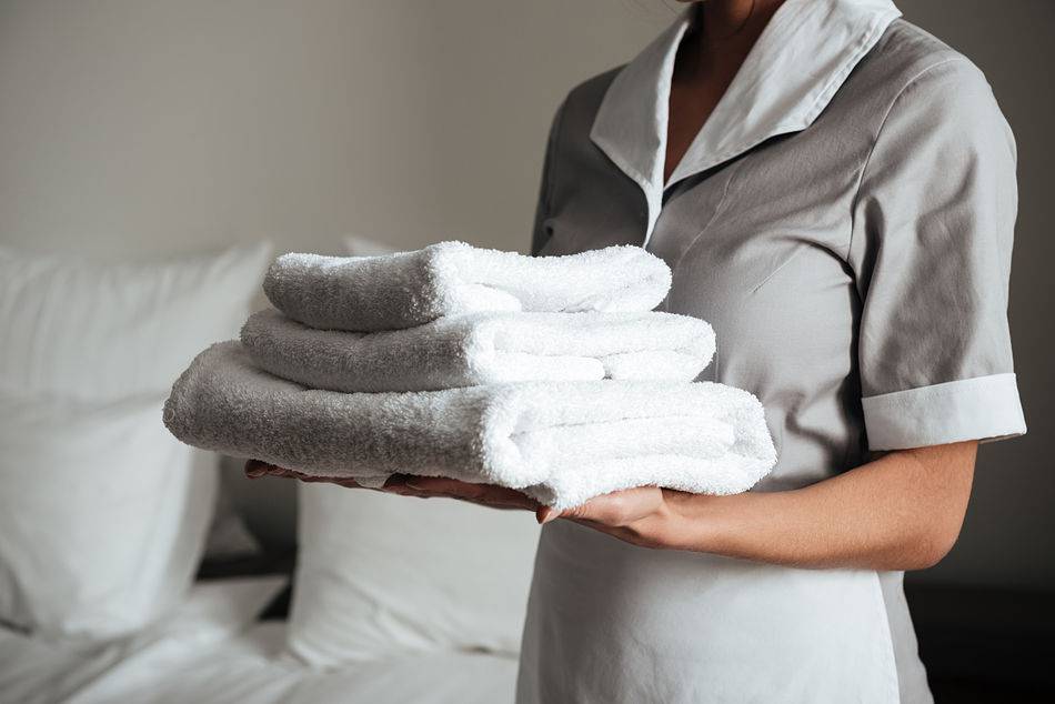 young hotel maid standing holding fresh clean towels 1 opt
